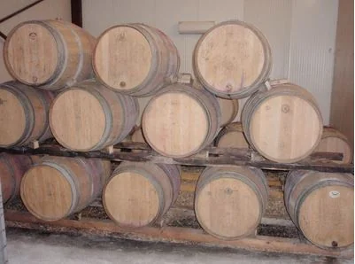 Photo authentique du chai : empilement de barriques en chêne sur palettes dans le cellier du domaine. 401x298 px. Image vraie et spécifique au domaine, mais basse résolution et composition modeste (lumière plate). Seule vue 'cave' disponible — utile pour la diversité, à utiliser en petit format.